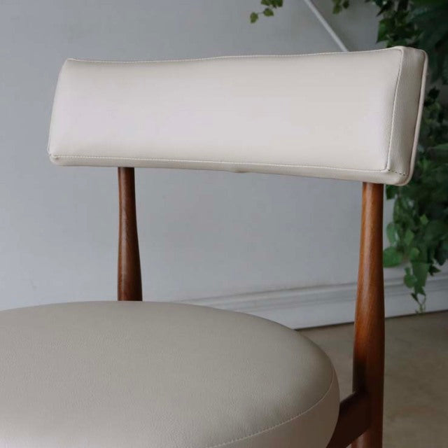 Mid-century British vintage teak dining chair with cream leather upholstery and tapered wooden legs.