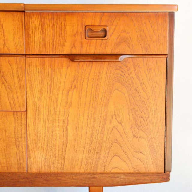 Mid-century British vintage teak sideboard with rich wood grain, recessed handles, and clean lines.