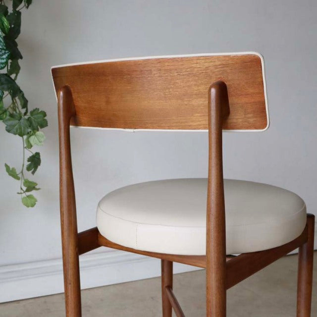 Set of two vintage G-plan mid-century dining chairs in teak with smooth wood grain and round cream upholstered seats.
