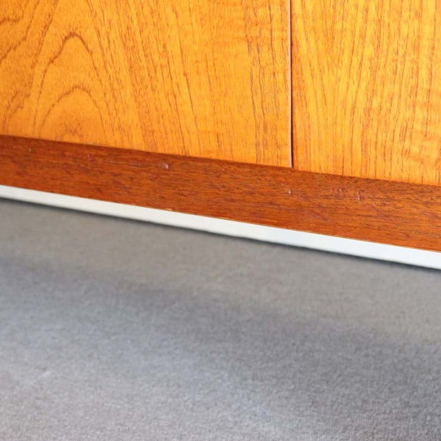 Mid-century British vintage teak sideboard with warm wood grain and clean lines resting on slender legs.