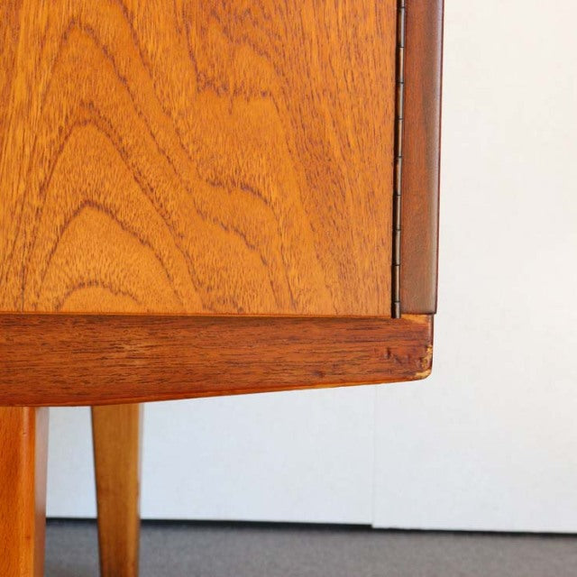 Close-up of vintage British mid-century teak sideboard corner showing wood grain and tapered leg detail.