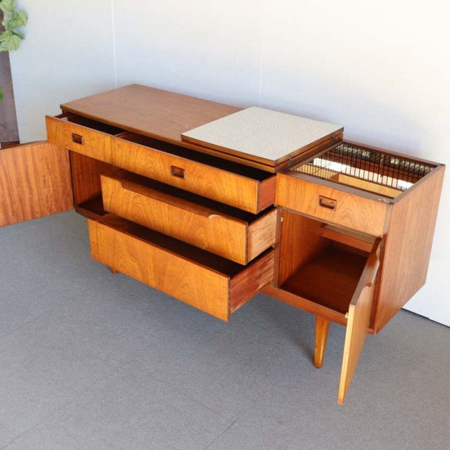 Mid-century British vintage teak sideboard with smooth wood grain, tapered legs, and open drawers showing clean interior.