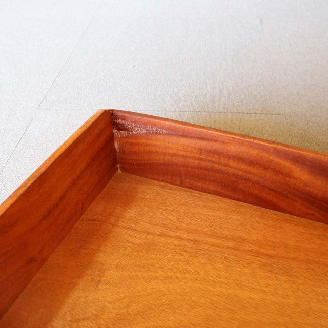 Close-up of vintage British mid-century teak sideboard corner showing warm wood grain and smooth craftsmanship.