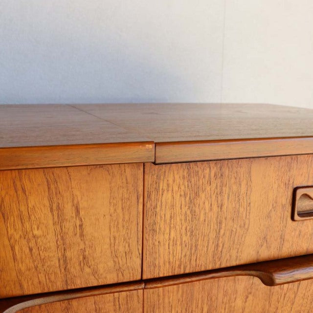 Mid-century British vintage teak sideboard with smooth wood grain and rounded edges, featuring integrated handles and.