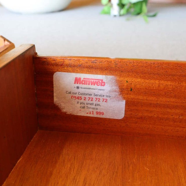 Close-up of teak wood interior showing rich grain and vintage label inside a British mid-century sideboard from Denmark.