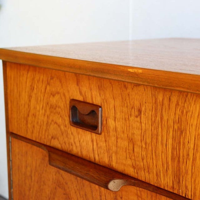 Vintage teak sideboard with mid-century British design, showcasing rich wood grain and rectangular brass drawer pull.