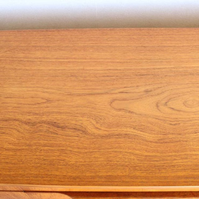 Smooth teak wood grain on vintage British mid-century sideboard surface with warm honey tones.