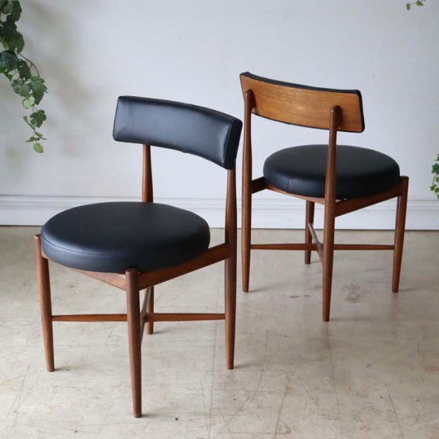 Set of four vintage G-Plan mid-century teak dining chairs with black leather seats and curved backrests, showcasing rich.