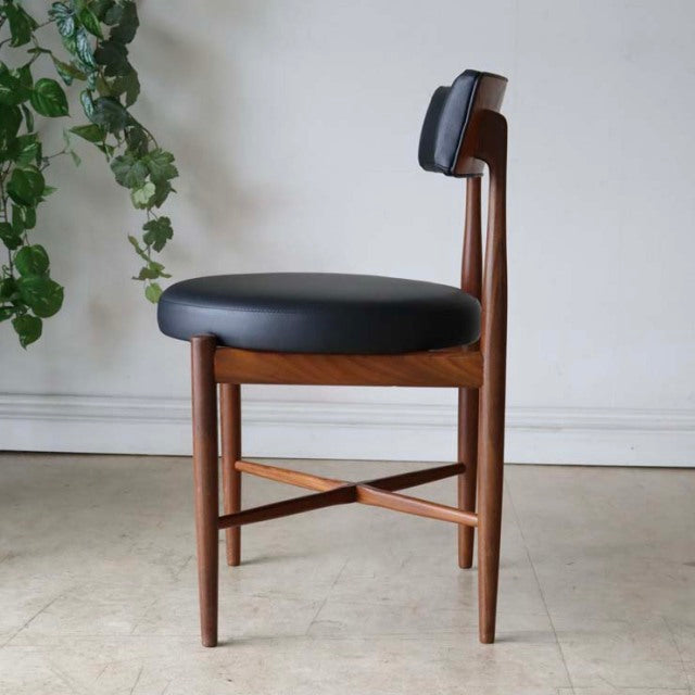 Mid-century British G-plan dining chair in rich teak with black leather seat and curved backrest, showcasing exposed wood.