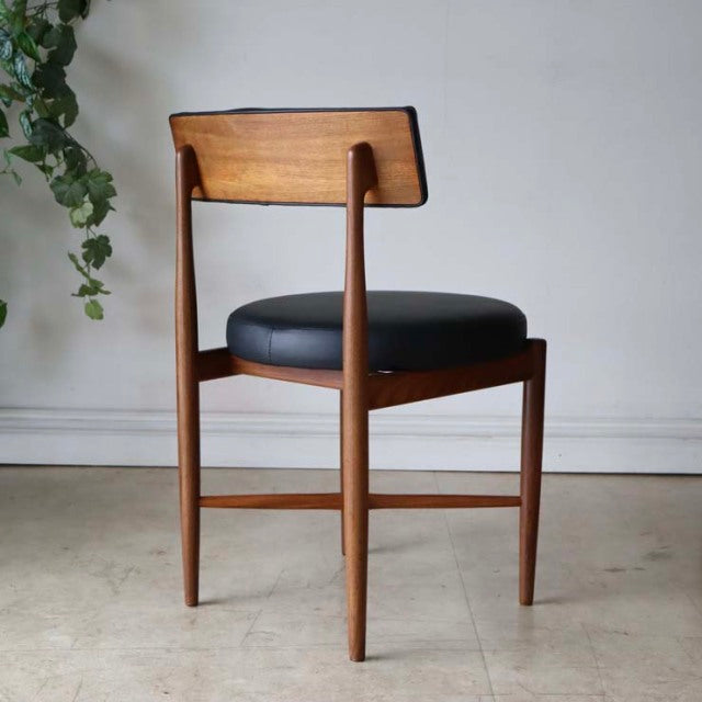 Vintage mid-century British G-Plan dining chair in teak with tapered legs and black cushioned seat.