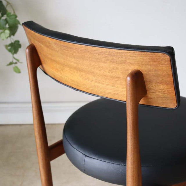 Mid-century British G-Plan vintage dining chair with curved teak backrest, black leather seat, and slender teak legs.