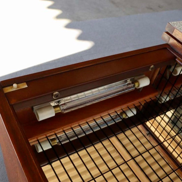 Close-up of vintage teak mid-century British sideboard interior with metal wire shelf and mounted fluorescent light fixture.