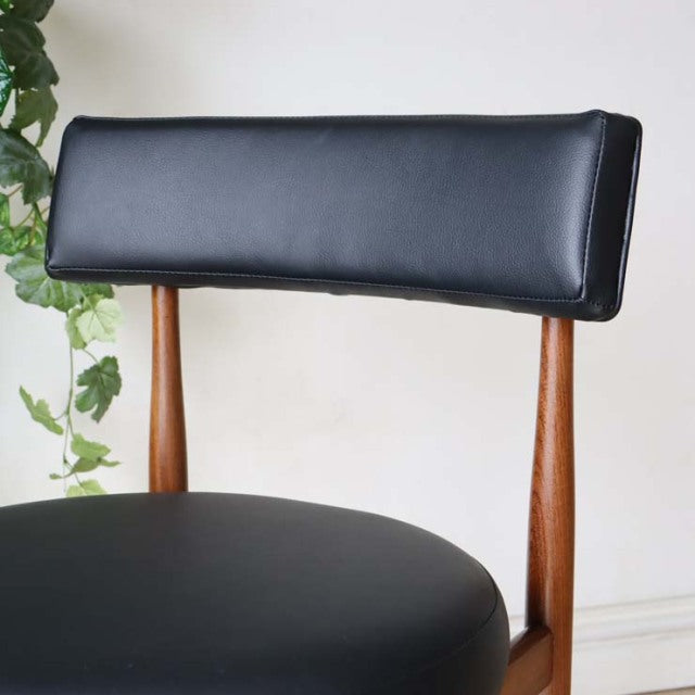 Mid-century British G-Plan dining chair in vintage teak with black leather seat and curved backrest, sleek wooden legs.
