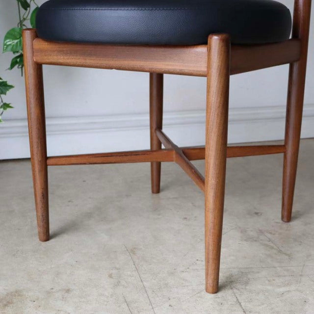 Set of four vintage G-plan teak dining chairs with tapered mid-century British-Denmark style legs and black upholstered seats.