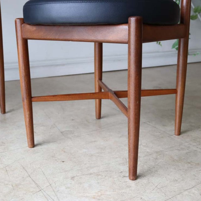 Set of four vintage G-plan mid-century teak dining chairs with black cushioned seats and tapered round wooden legs in.