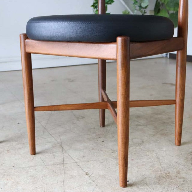 Mid-century vintage British G-PLAN dining chair in teak with smooth wood grain and black cushioned seat, slender tapered.