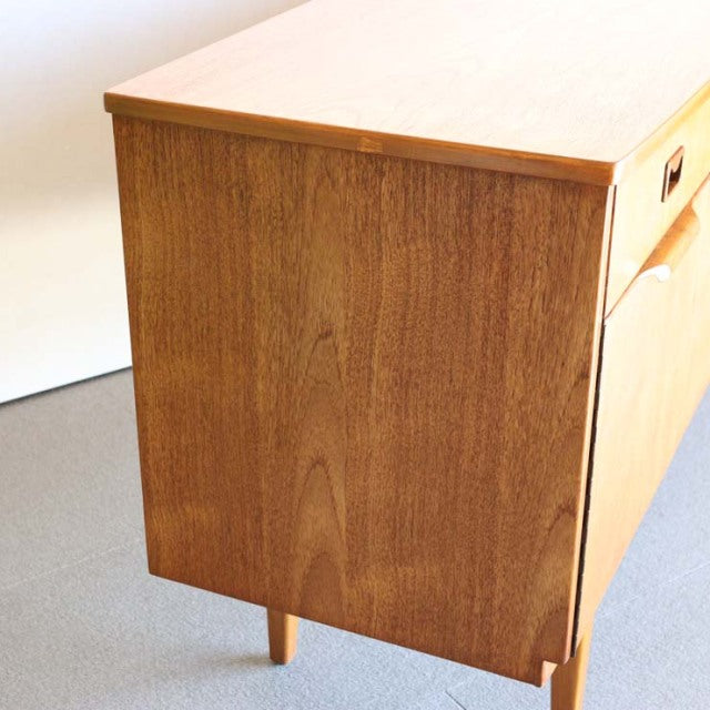 Mid-century vintage teak sideboard with British and Danish design influences, smooth wood grain, tapered legs, and.