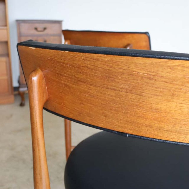 Set of four British mid-century G-Plan dining chairs in vintage teak with black upholstered seats and elegant tapered legs.