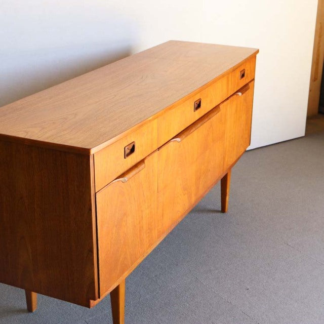 Mid-century British vintage teak sideboard with clean lines, square recessed handles, and tapered legs showing warm wood.