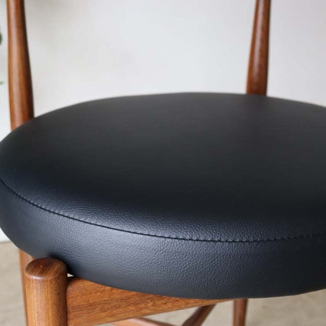 Mid-century British G-Plan vintage teak dining chair with smooth black leather seat and tapered wooden legs.