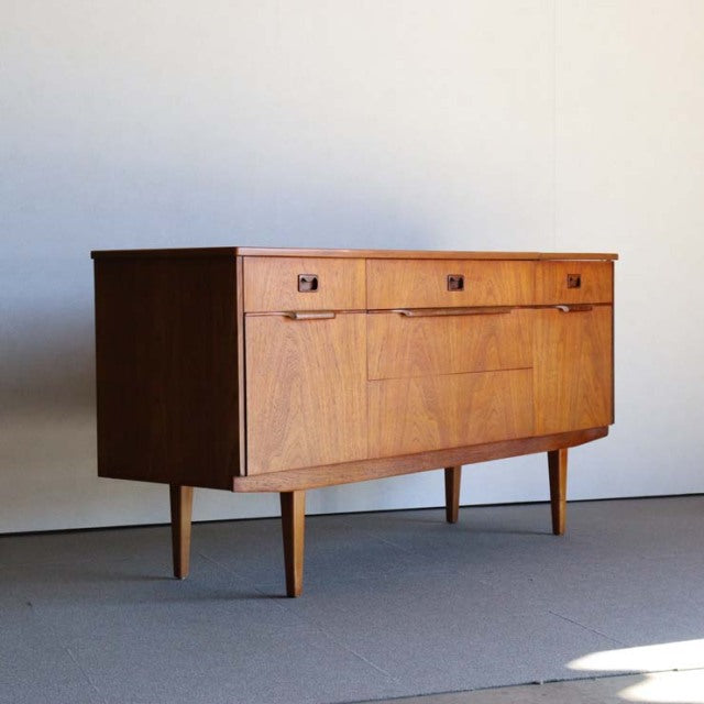 Mid-century British vintage teak sideboard with smooth wood grain, square handles, and tapered legs from Denmark design.