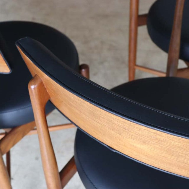 Set of four vintage G-Plan mid-century British dining chairs with teak frames and black curved vinyl seats and backs,.