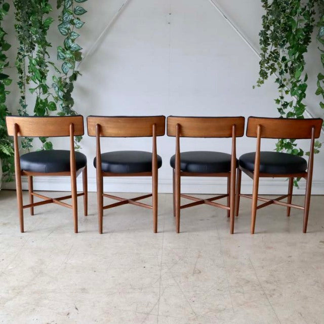 Set of four vintage G-Plan mid-century teak dining chairs with black leather seats and straight tapered legs.