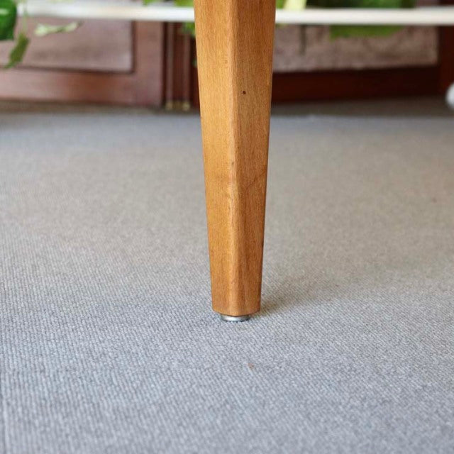Tapered teak leg of British mid-century vintage sideboard with visible wood grain and brass foot cap.