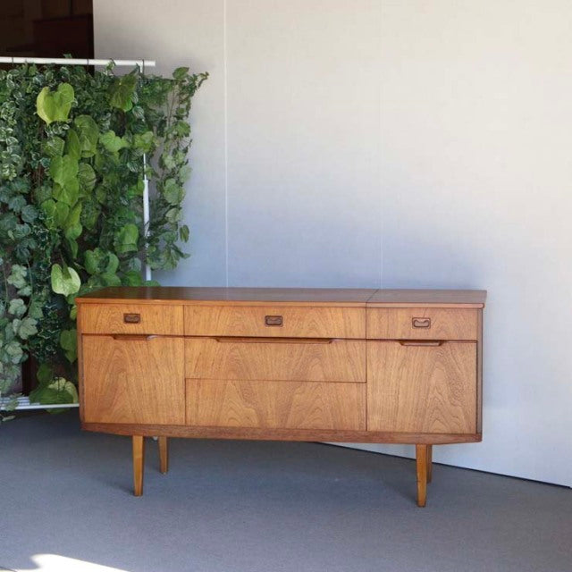Vintage British teak sideboard with mid-century sleek lines, tapered legs, and rich wood grain detailing.