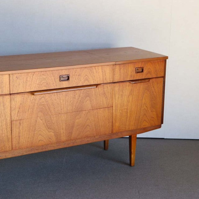 Mid-century vintage teak sideboard with rich wood grain, tapered legs, and minimalist British design from Denmark.