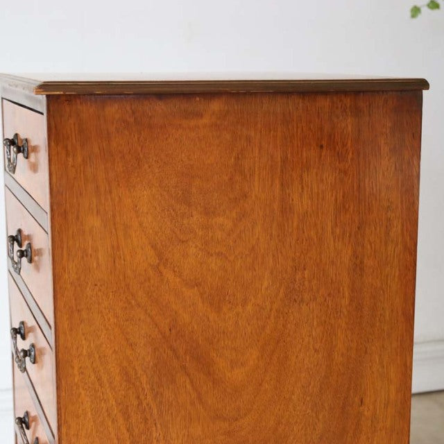 Mid-century British vintage teak cabinet with rich wood grain and round wooden drawer pulls, sleek tapered legs.