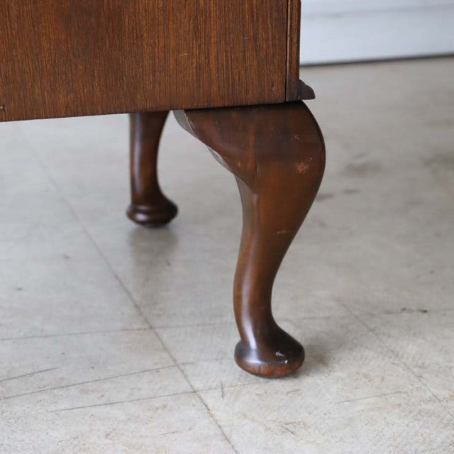 Close-up of vintage British teak record cabinet leg with mid-century curved clawfoot design and rich wood grain finish.