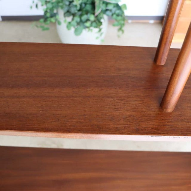 Vintage teak shelving with smooth wood grain and slender British mid-century Denmark iron legs in warm finish.