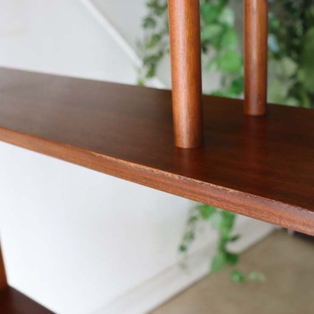 Close-up of vintage teak wood shelf with clear grain and rounded British mid-century Denmark-style iron legs in warm brown.