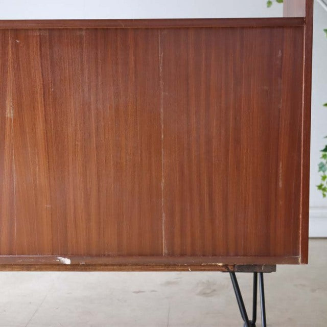 Vintage teak room divider with smooth British mid-century wood grain and slender Danish iron legs.
