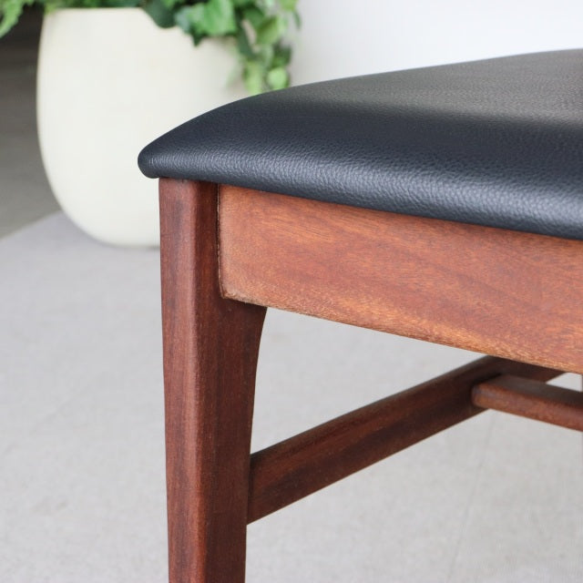 Mid-century British teak dining chair with black leatherette seat, showcasing rich wood grain and sturdy square legs from.