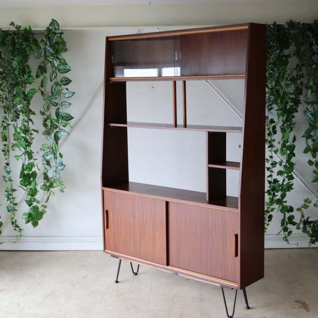 Mid-century British vintage teak room divider with iron hairpin legs, integrated shelving, and sliding cabinet doors,.