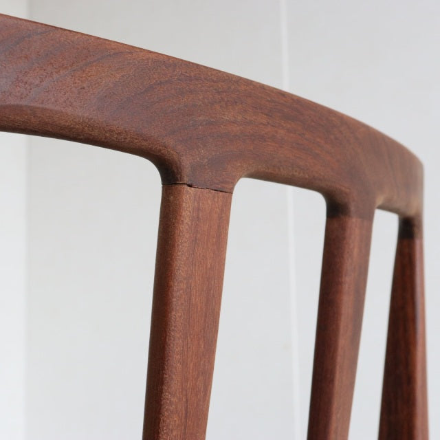 Close-up of vintage teak dining chair backrest with smooth rounded edges and rich wood grain from British Younger Fonseca.