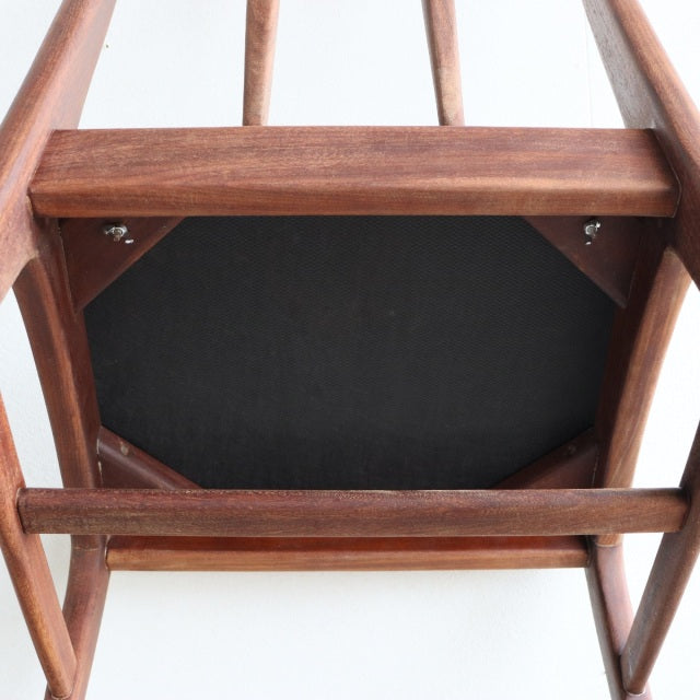 Underside view of vintage British mid-century teak dining chair frame by Younger with visible wood grain and black seat base .