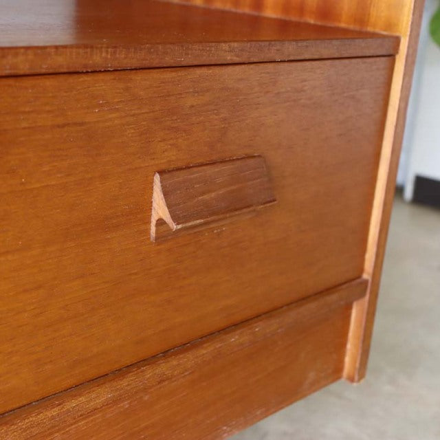 Close-up of vintage teak wood TV board drawer front with British mid-century design and natural wood grain details.