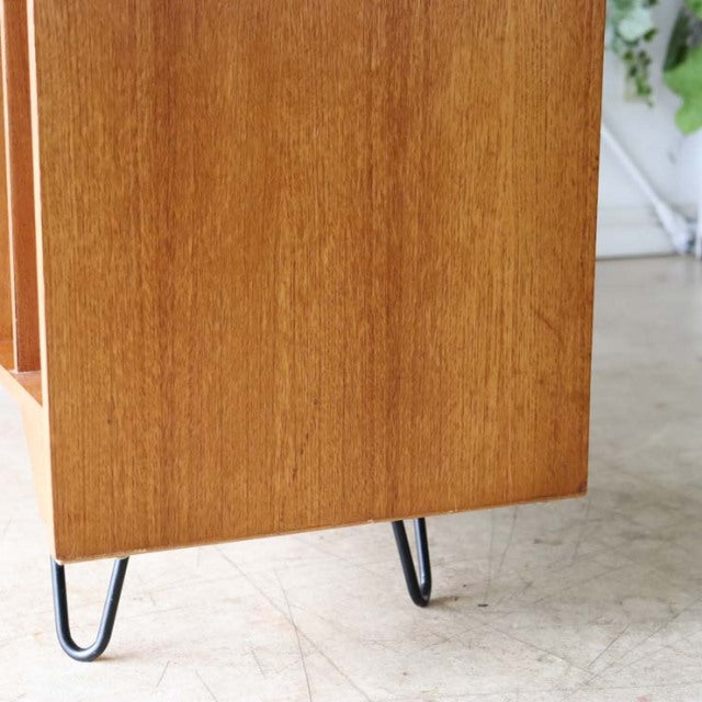 Mid-century vintage teak TV board corner showing smooth wood grain and slender British iron hairpin legs in natural light.
