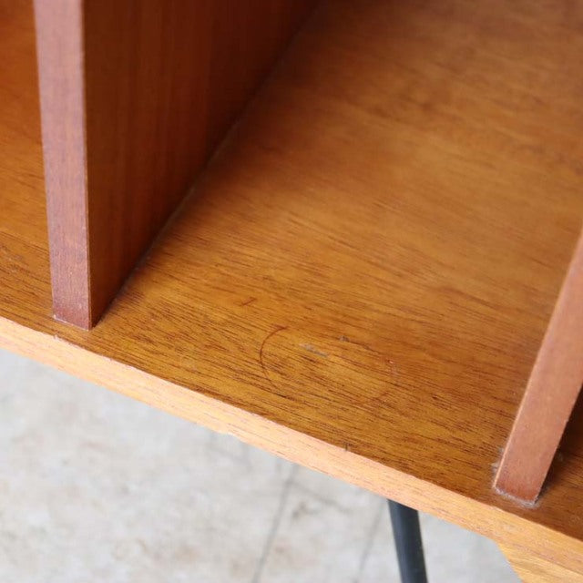 Close-up of vintage teak wood grain on British mid-century TV board with slender iron legs and warm natural finish.