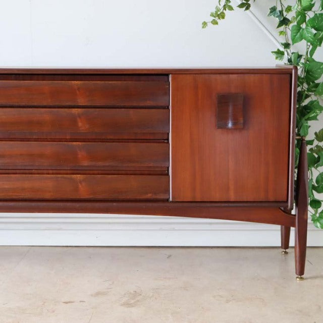 Mid-century British vintage teak sideboard with rich wood grain, horizontal drawers, and slender tapered legs with brass.