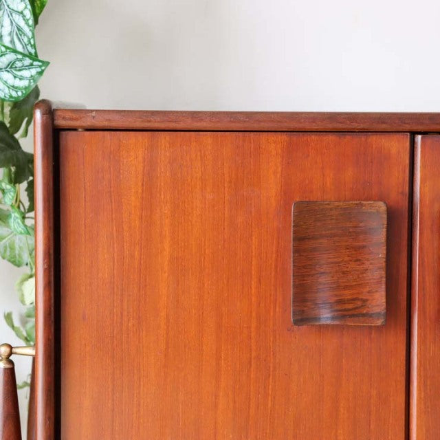 British mid-century teak sideboard with rich wood grain, rounded edges, and a square wooden handle.