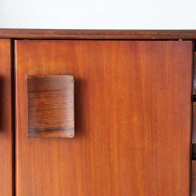 Vintage teak mid-century British sideboard with rich wood grain and unique rectangular handle on floating-style door panel.