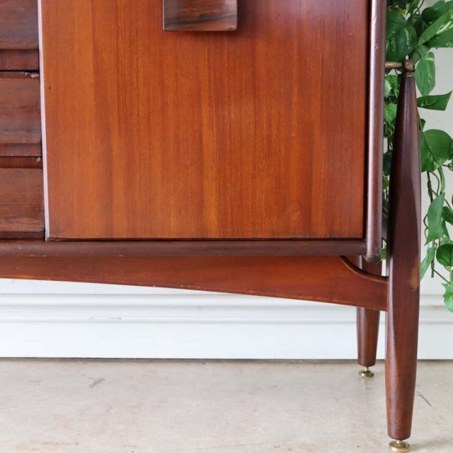 Vintage British mid-century teak sideboard corner with rich wood grain, tapered legs, and floating style credenza design.
