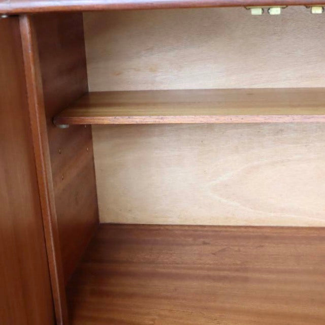 Close-up of vintage British mid-century teak sideboard interior showing warm wood grain and smooth shelf surface with clean.