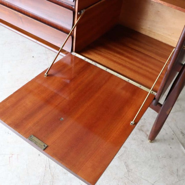 Mid-century British teak sideboard with zebrano wood grain, drop-down door, brass hinges, and slender tapered legs.