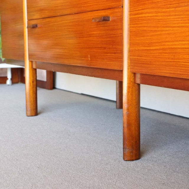 Mid-century British vintage teak sideboard with warm wood grain and rounded cylindrical legs, showcasing authentic.
