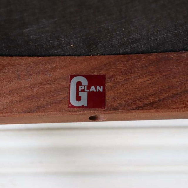 Close-up of teak wood frame on British mid-century G-PLAN chair, showcasing rich wood grain and Fresco series metal logo.